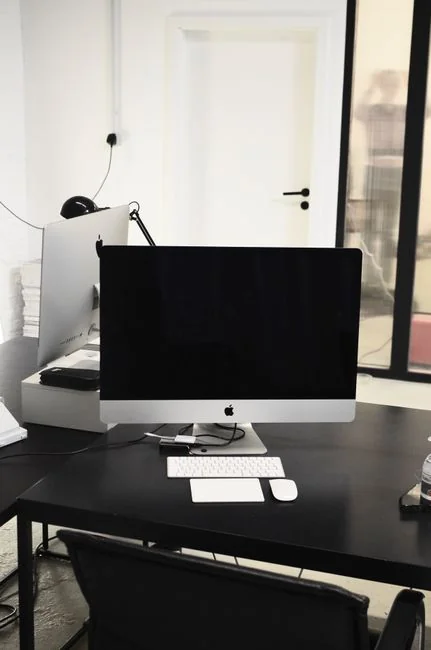 A MacBook Pro showing Google Search on a wooden table outside, beside a smartphone.